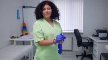 Zeki, kendine güveni tam bir doktor. Kapalı bir hastanede ameliyat eldiveni takıyor. Kameraya gülümseyen beyaz kadın portresi. Uzmanlık ve yaşam tarzı kavramı