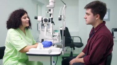 Doktor içeride hastaya otomatik fraktör tanısı koyarak konuşuyor. Oftalmoloji kliniğinde profesyonel ekipmanlarla danışmanlık yapan beyaz kadın portresi