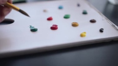Yakın plan kadın eli fırçayla birlikte akrilik boya alıyor. Tanımlanamayan yetenekli beyaz bir kadının kapalı alanda resim çizmesine ilham kaynağı oldu. Yetenek ve ilham konsepti