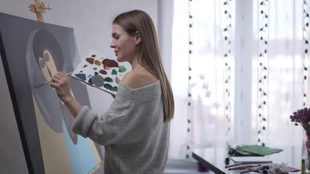 Talented Cheerful Young Woman Painting Canvas Waving Looking Away Smiling — Vídeo de Stock