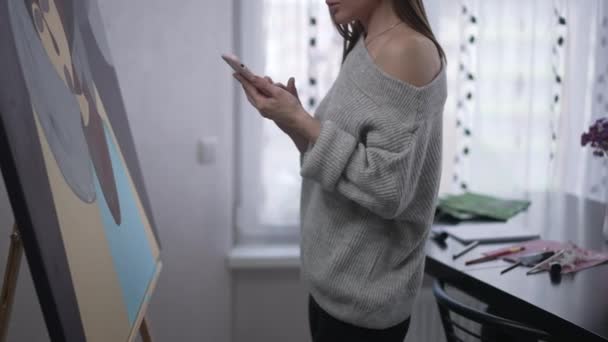 Unrecognizable Young Woman Standing Easel Picture Surfing Social Media Smartphone — Vídeo de stock