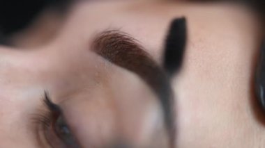 Mikroplu patinaj işleminden sonra güzellik salonunda yakın plan fırçalama, kadın kaşları. Kaplıcada, fırçayla şekillendirilmiş güzellik uzmanı eli olan beyaz bir müşteri. Güzellik ve dövme.