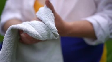 Close-up unrecognizable woman drying hands in slow motion with white towel outdoors. Plus-size overweight Caucasian lady rubbing palms with cloth after washing. Hygiene and lifestyle