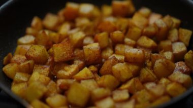 Close-up potato frying on cooking pan in kitchen indoors. Vegetable roasting in sunflower oil closeup