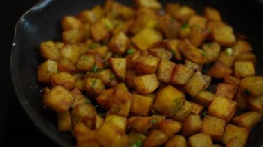 Top view cooked delicious fried potato with dill in kitchen indoors. Tasty dinner on cooking pan close-up