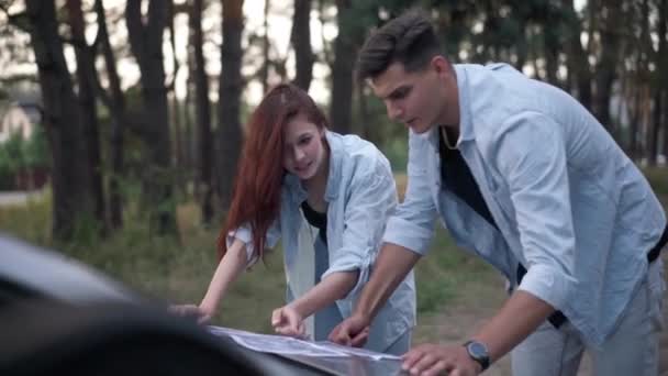 Positive Couple Talking Gesturing Examining Paper Map Car Hood Forest — Wideo stockowe