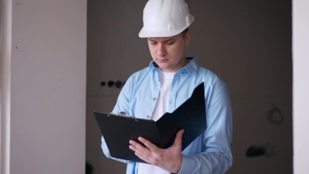 Concentrated Caucasian Male Builder Hard Hat Checking New Flat Looking — 图库视频影像