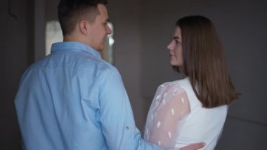 Back view man hugging woman discussing new apartment renovation with spouse. Happy loving Caucasian young couple planning repair and moving in