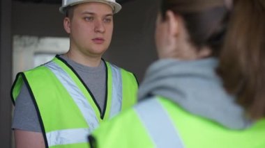 Portrait of male builder listening female foreperson talking smiling. Confident professional Caucasian man and woman discussing renovation planning repair standing in new flat