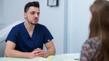 Expert Middle Eastern handsome doctor talking shaking hands with Caucasian patient. Portrait of confident professional plastic surgeon sitting on the left handshaking with woman in medical clinic