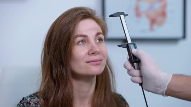 Close Positive Caucasian Woman Looking Unrecognizable Doctor Measuring Face Vernier — Vídeos de Stock