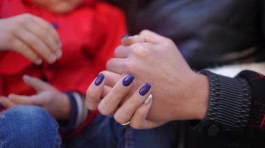 Kapalı çekim çocuk eli, kadın avuç içlerine dokunuyor. Tanımlanamayan beyaz bir çocuk ve genç bir anne arka bahçede birlikte. Aile sevgisi ve birlik kavramı