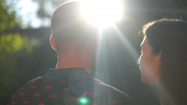 Arkadan bakan, sevgi dolu kadın güneş ışığıyla başını erkeğin omzuna koyuyor. Açık havada gün batımına hayran olan genç, beyaz bir çift. İlişki ve romantizm kavramı