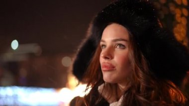 Yakın plan depresyonda olan genç bir kadın Noel gecesi şehir merkezinde durup düşünüyor. Üzücü Kafkas bayanı Yeni Yıl arifesinde yalnız, arka planda kar yağışı var.