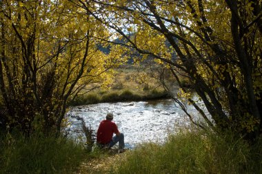 adam oturmuş ve nehir kenarında düşünme