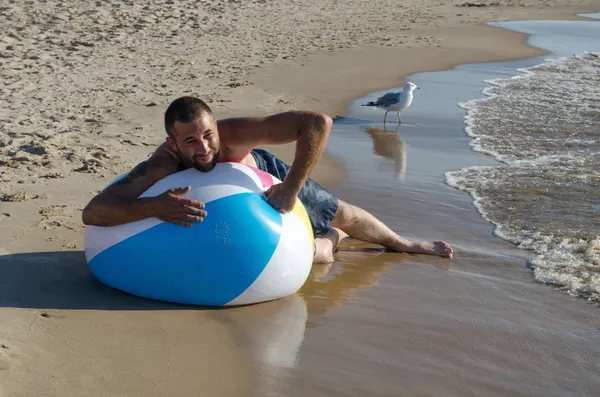 Homem desinflando uma bola de praia — Fotografia de Stock