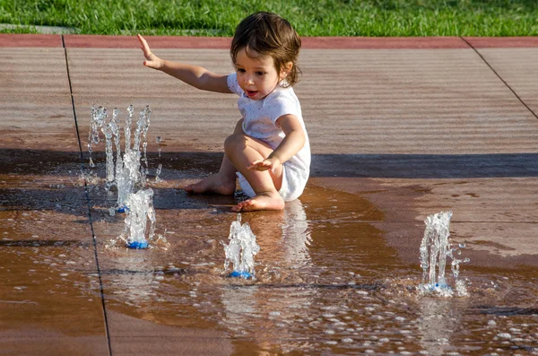Тоддлер играет с водой в городском фонтане — стоковое фото