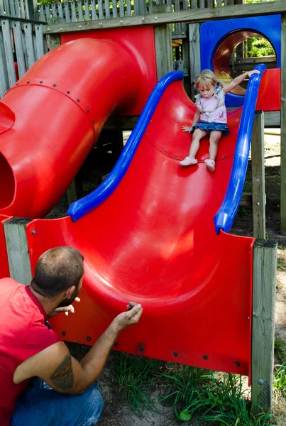 Papa fängt kleines Mädchen auf Spielplatz-Rutsche — Stockfoto