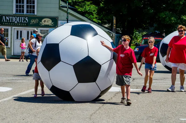 Kids rolling giant soccer balls — Stock Photo, Image