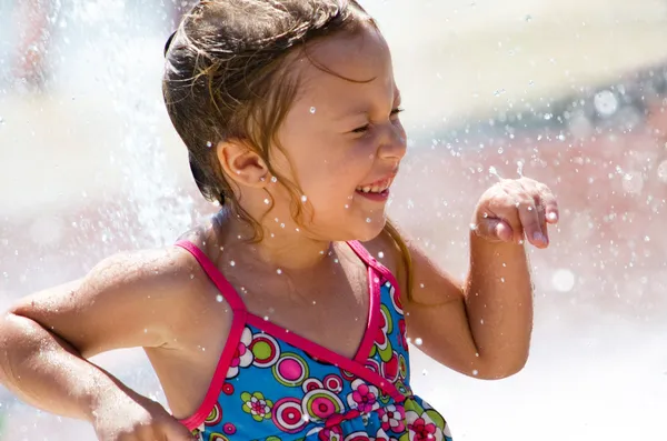 Laughing girl being showered in a fountain — Stock Photo, Image