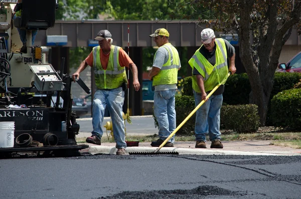 Trabajadores de la carretera rastrillando asfalto caliente — Foto de Stock