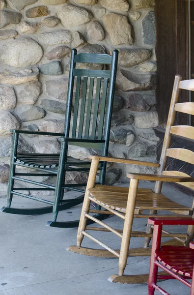 Cadeiras de balanço em cores diferentes em um alpendre — Fotografia de Stock