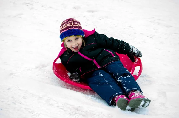 Kind lachen als ze sleeën in een heuvel — Stockfoto