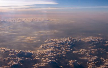 Ülkeyi boydan boya geçen bir uçak yolculuğu sırasında bulutlar arasında filtrelenen güneş ışınları