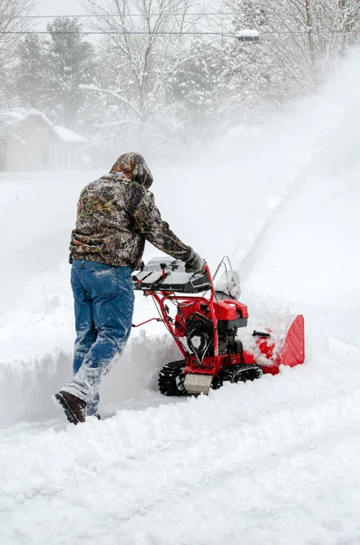 強硬労働者は冬の嵐の後に深い雪をきれいにするために雪ブロワーを使用します — ストック写真