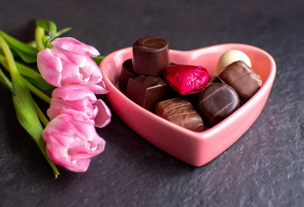 粉红的郁金香和粉红的心糖盘 里面塞满了美味的巧克力 — 图库照片