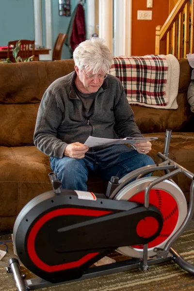 An older man reads instructions on how to assemble a new exercise bike