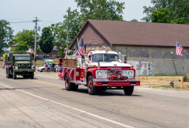 Eau Claire MI USA, 4 Temmuz 2022, Amerikan bayraklarıyla süslenmiş antika bir itfaiye aracı, bu 4 Temmuz geçit töreninde eski bir ordu kamyonu tarafından takip ediliyor.