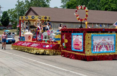 Eau Claire MI ABD 4 Temmuz 2022, lise güzellik yarışması kraliyet ailesi, bu 4 Temmuz geçit töreninde renkli bir şamandıraya binerken kalabalığa el sallayın.