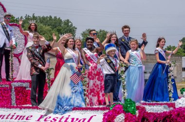Eau Claire MI USA, 4 Temmuz 2022; mutlu gençler ve genç, gösterişli kıyafetler ve parıltılı tacını gururla gösterirken renkli bir şamandıradan ışık ve el sallıyorlar.