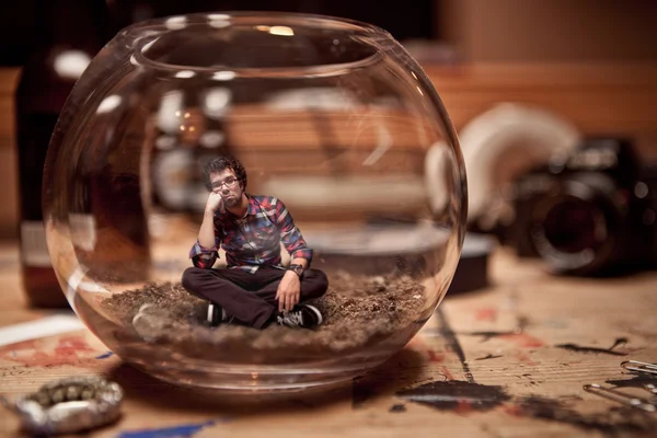 Unhappy Miniature man trapped inside a fishbowl. — Stock Photo, Image