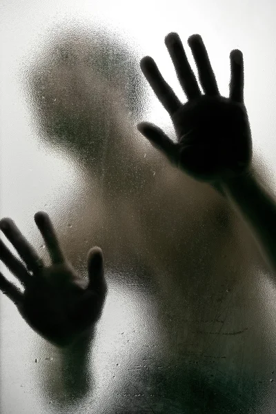 Silhouette of a man with hands on a frosted glass — Stock Photo, Image