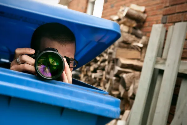 Paparazzi escondido en un cubo de basura azul Fotos de stock