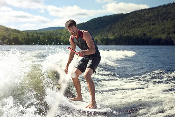 Wakesurfing szczęśliwy przystojny mężczyzna w jeziorze — Zdjęcie stockowe