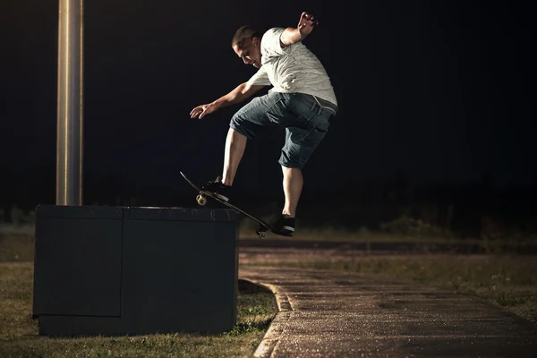 Скейтбордист выполнял трюк с бортовой горки ночью — стоковое фото