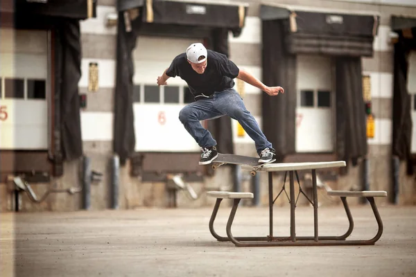 Skater robi Krzywy grind na stole piknikowym — Zdjęcie stockowe