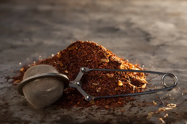 Rooibos Té y colador de té en una textura metálica —  Fotos de Stock