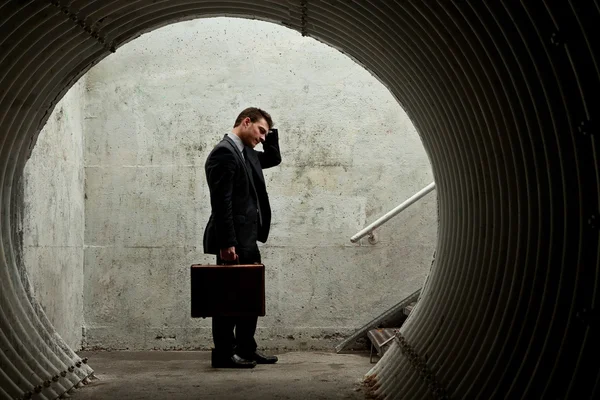 绝望商人抱着头在一个黑暗的隧道. — 图库照片