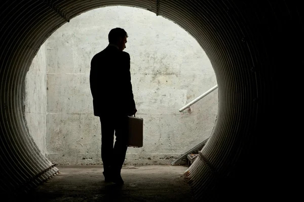 Geschäftsmann in Silhouette läuft in einem dunklen Tunnel Stockbild