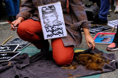 Mahsa Amini 'nin ölümünden sonra 23 Eylül 2022' de Belçika 'nın Brüksel kentindeki İran Büyükelçiliği önünde düzenlenen gösteride bir kadın saçını kesti..