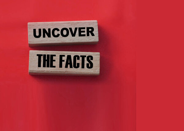 Uncover the facts word on wooden blocks on red background. Fake or real news business concept.