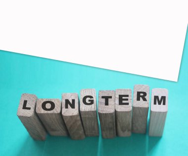 Cyan açık mavi arka planda tahta küplerle ilgili uzun vadeli bir kelime. Güvenilir iş uzun vadeli ilişki kavramı.