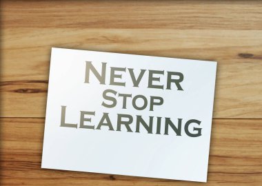 Metin asla sayfada öğrenmeyi bırakmaz, tahta masada dolar işaretleri. eğitim kavramı