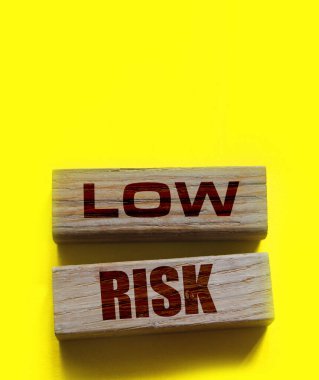 Düşük riskli kelimeler sarı üzerine tahta bloklar. İş yatırımları konsepti riske atıyor.