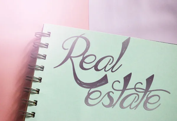 在螺旋式复制书页上写着的房地产字被涂上了粉红色的背景 有选择的重点 房地产投资租赁业务概念 — 图库照片