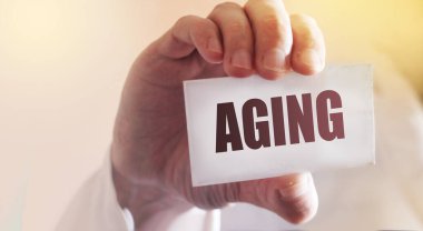 Doktor içinde yaşlanma olan bir kart tutuyor. Seçici odaklanma. Tıbbi konsept.